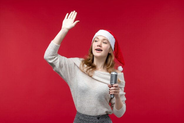 Вид спереди симпатичной женщины, держащей микрофон и размахивающей красным