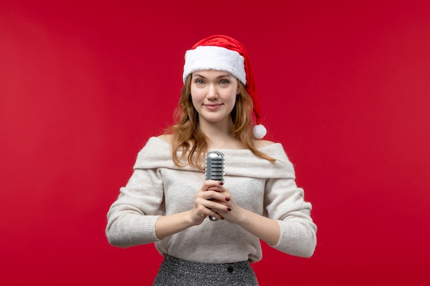 Front view of pretty female holding mic with smile on red