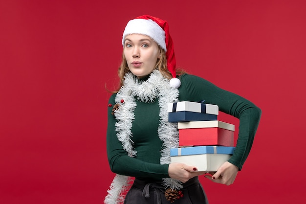 Front view pretty female holding new year presents on red background