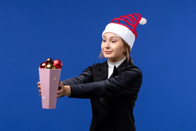 Front view pretty female holding plastic tree toys on blue desk blue holiday new year