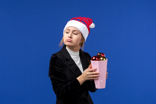 Front view pretty female holding plastic tree toys on blue floor blue holiday new year