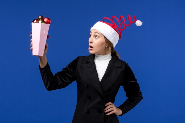 青い壁の青い新年の休日にプラスチック製の木のおもちゃを保持している正面図きれいな女性