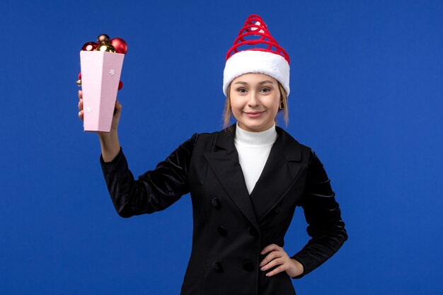 Front view pretty female holding plastic tree toys on a blue wall new year holiday blue