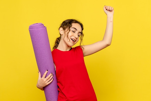 Front view of pretty female holding purple carpet on yellow