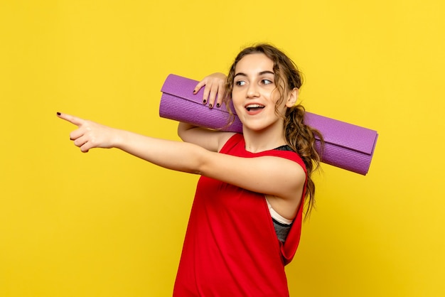 Foto gratuita vista frontale della femmina graziosa che tiene tappeto viola su giallo