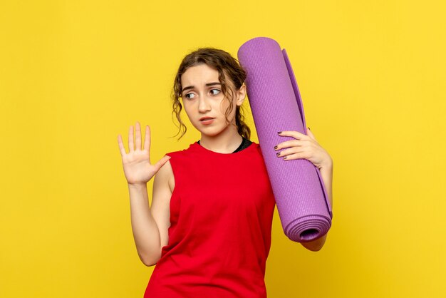 黄色の紫色のカーペットを保持しているきれいな女性の正面図