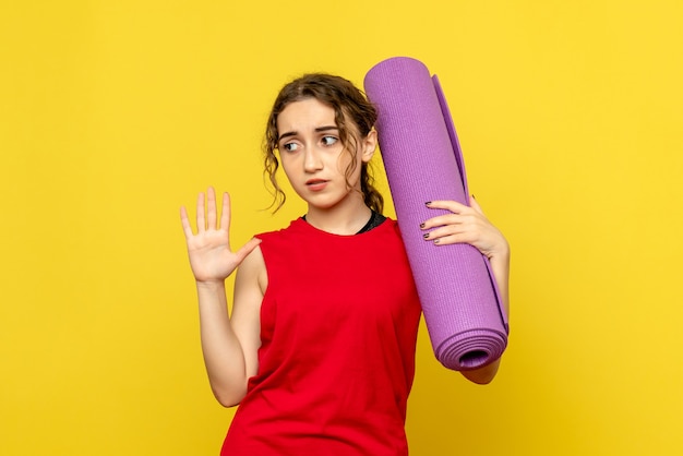 Front view of pretty female holding purple carpet on yellow