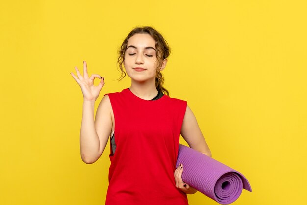 Free photo front view of pretty female holding purple carpet on yellow