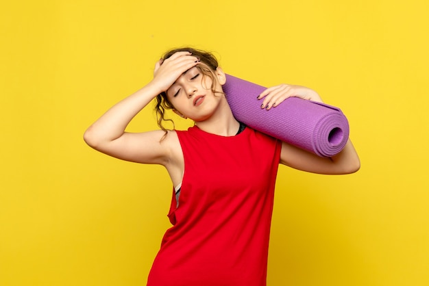 Free photo front view of pretty female holding purple carpet on yellow