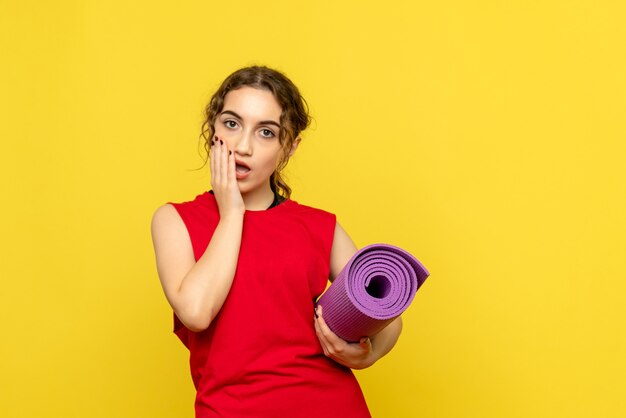 Front view of pretty female holding purple carpet on yellow