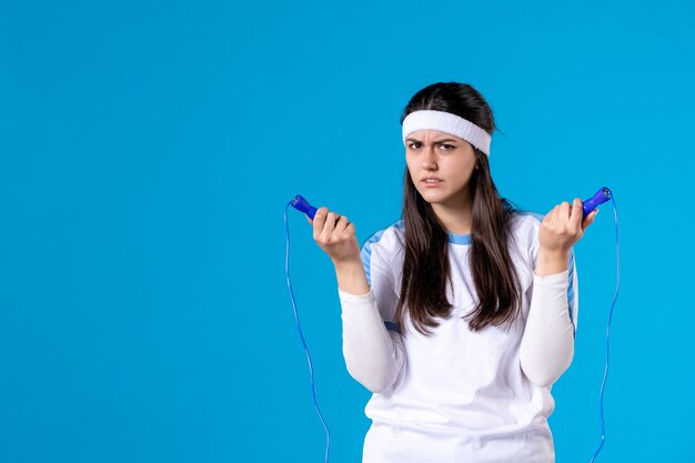 Front view pretty female holding skipping rope on blue 