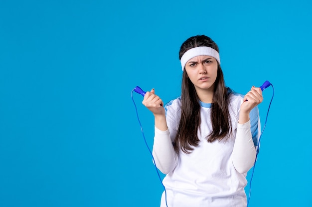 Front view pretty female holding skipping rope on blue 