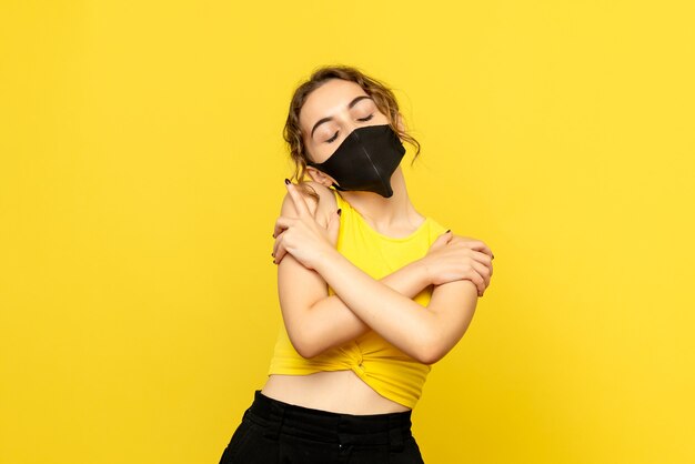 Front view of pretty female hugging herself on yellow