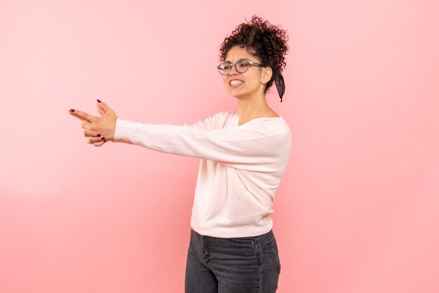 ピンクの銃のポーズを模倣したきれいな女性の正面図