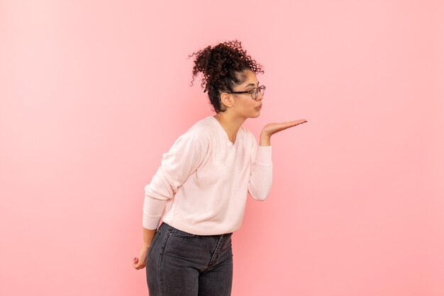 Front view of pretty female sending kisses on pink