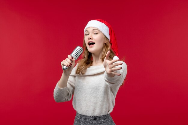 Front view of pretty female singing with mic on red