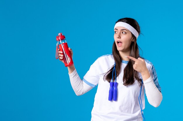 Front view pretty female in sport clothes with skipping rope on blue 