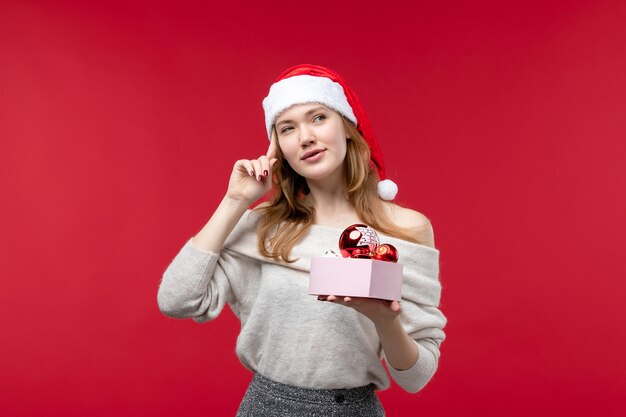 Вид спереди красивой женщины с рождественскими игрушками на красном