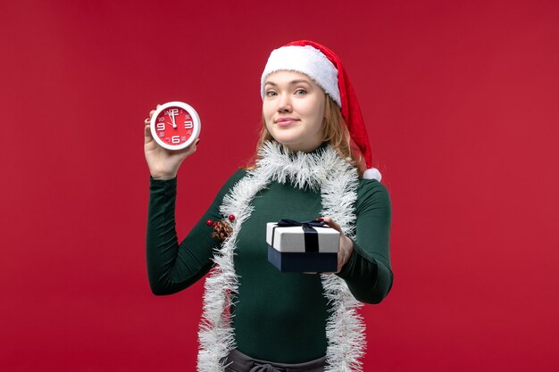 Free photo front view pretty female with presents with clock on red background