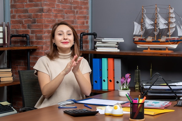 Front view of pretty woman clapping hands working in office