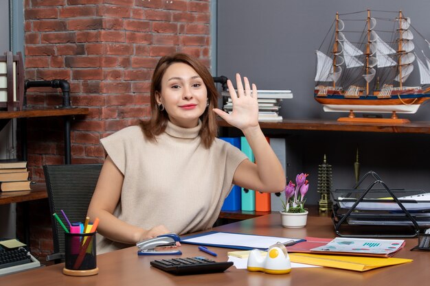 Vista frontale di una bella donna che saluta qualcuno che lavora in ufficio