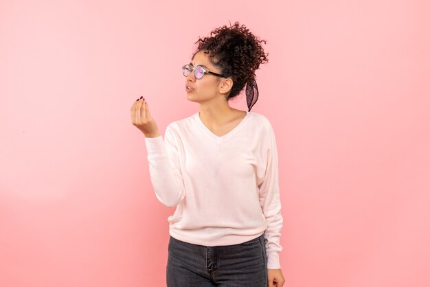 Front view of pretty woman talking to someone on pink wall