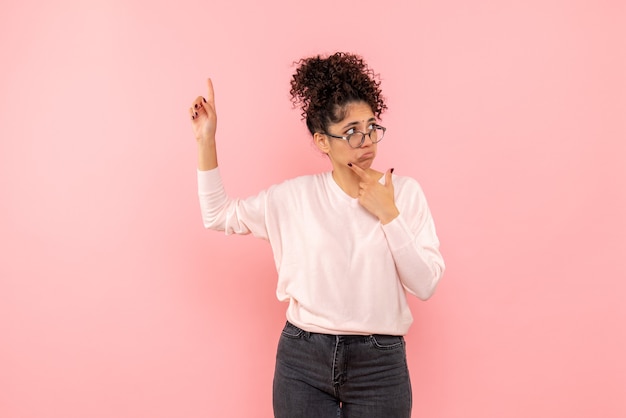 Front view of pretty woman thinking on a pink wall