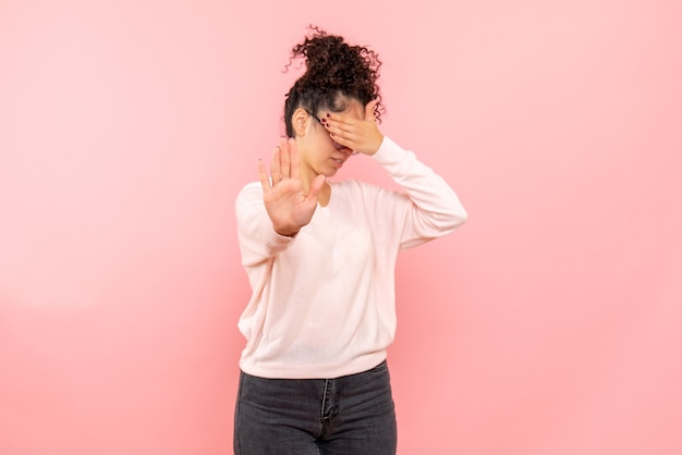 Free photo front view of pretty woman with covered face on pink wall