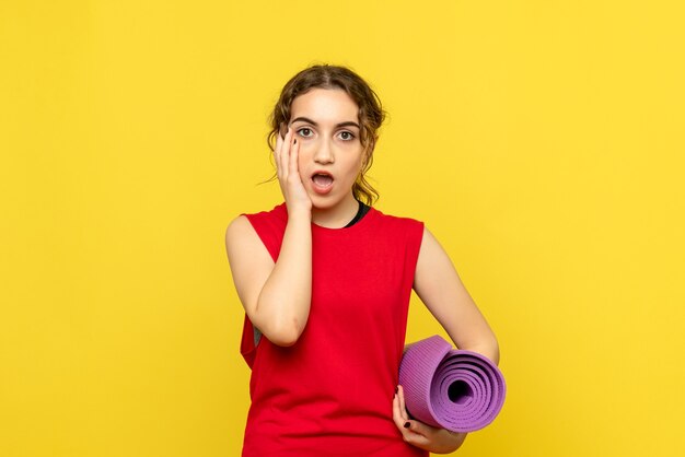 Front view of pretty woman with purple carpet on yellow wall