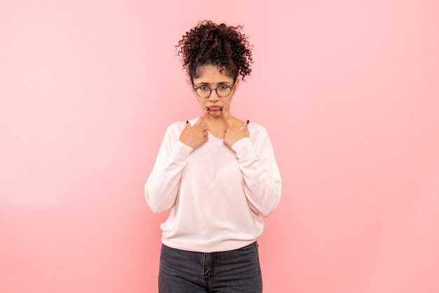 Front view of pretty woman with sad face on pink wall