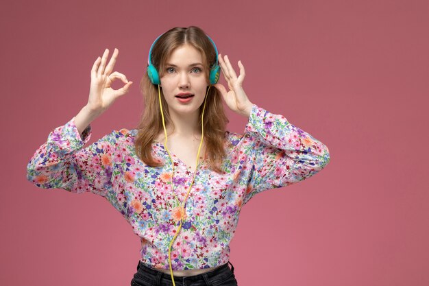 Front view pretty young woman shows everything is alright with her fingers and listening to music