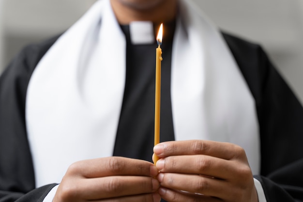 Священник, вид спереди, держит свечу
