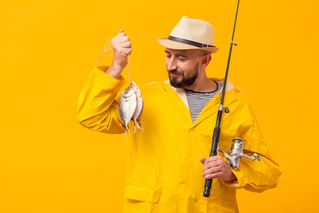 Front view of proud fisherman holding catch and fishing rod