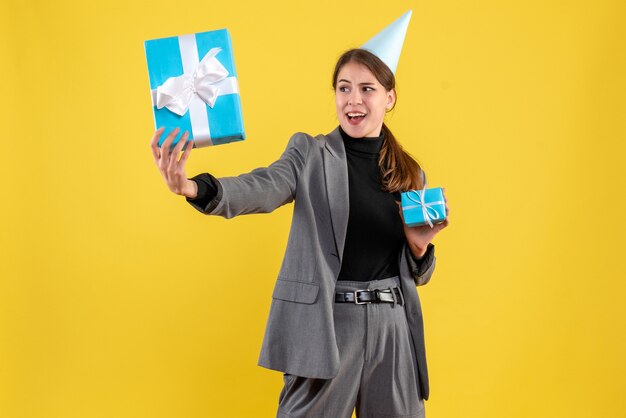 Front view prying girl with party cap looking at xmas gifts