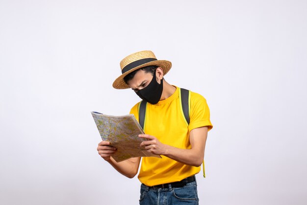 Front view prying young man with mask and yellow t-shirt looking at map