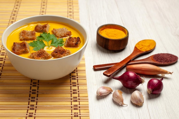 Front view pumpkin soup with little bread rusks and garlics on the white space