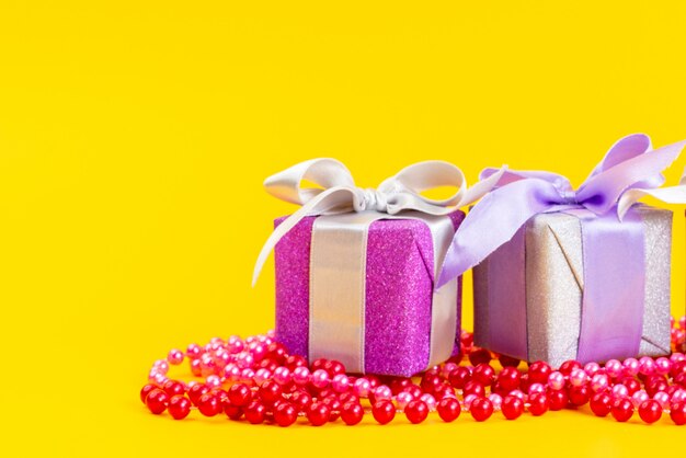 A front view purple gift boxes with bows on yellow