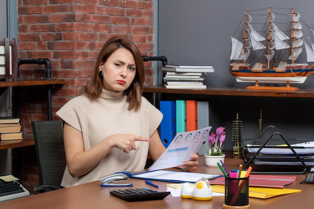 Foto gratuita vista frontale della donna graziosa perplessa che tiene i documenti che lavorano in ufficio