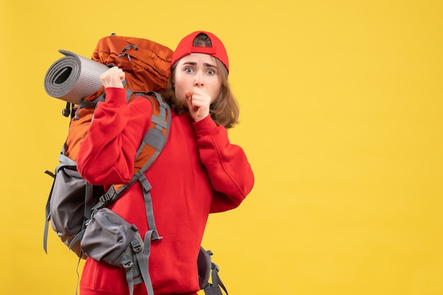 Front view puzzled traveller woman in red backpack standing on yelow wall