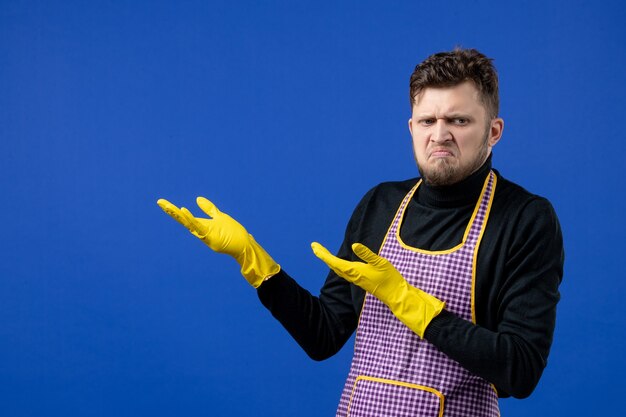 Front view of puzzled young man standing on blue wall