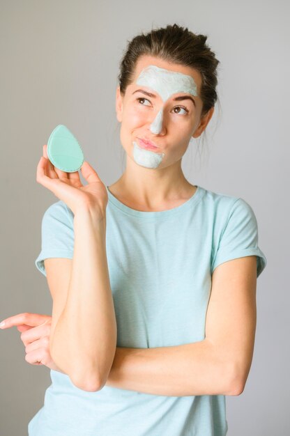 Front view of quirky woman posing with face cream on