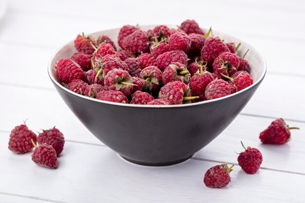 Front view of raspberries in a bowl on a white surface