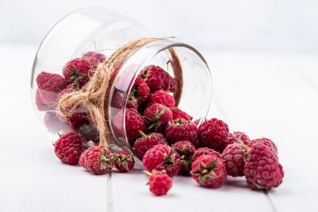 Front view of raspberries in a jar on a white surface