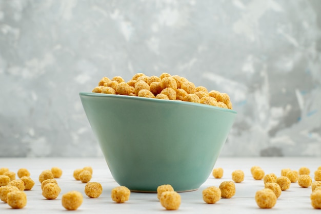 Front view raw cereals yellow colored inside green plate on white, cereal breakfast cornflakes health