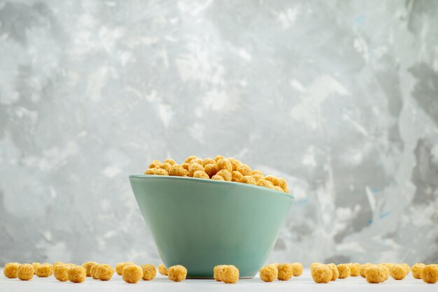 Front view raw cereals yellow colored inside green plate on white, cereal breakfast cornflakes health