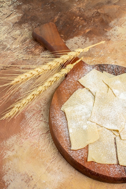 Foto gratuita vista frontale fette di pasta cruda con farina su una cucina di piatto di pasta scrivania crema