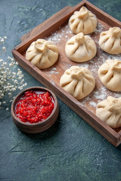 Front view raw dumplings with meat inside on dark gray surface cooking dish color meal flour pepper dough meat