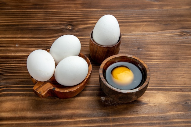 Free photo front view raw eggs whole products on brown wooden surface egg food meal breakfast scrambled eggs