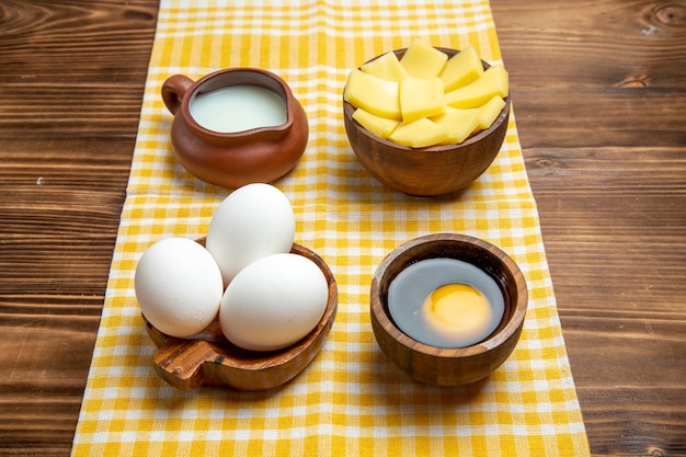 Front view raw eggs with cheese and milk on a wooden surface product eggs dough meal food raw