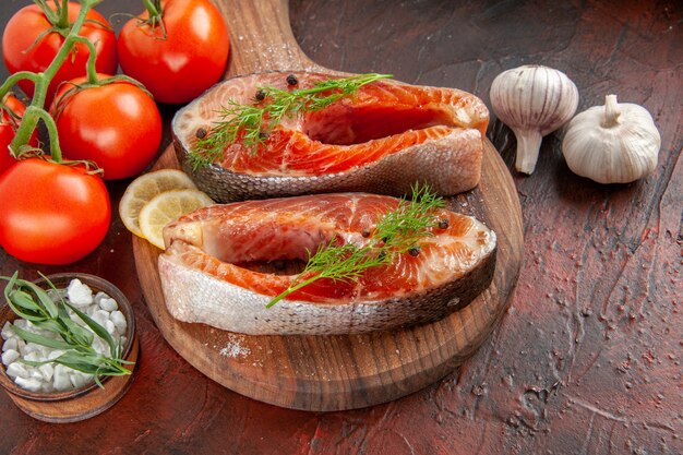 Вид спереди кусочки сырой рыбы с красными помидорами на темно-красном цвете мяса фото еда барбекю блюдо из морепродуктов